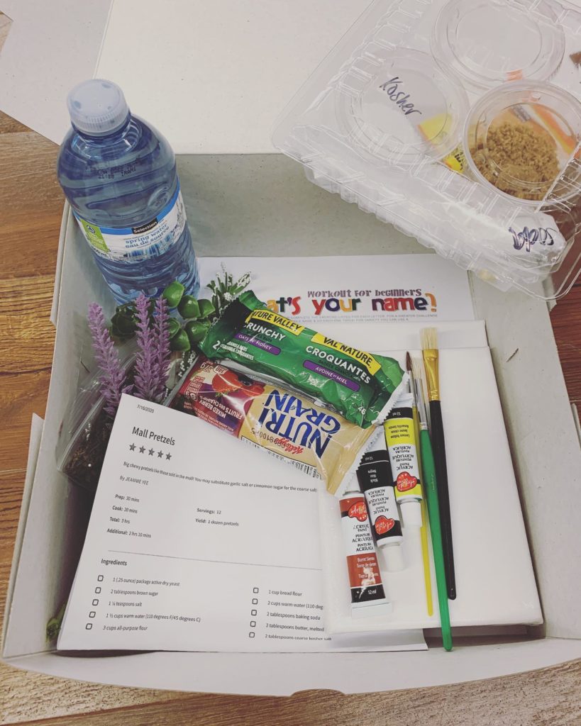 An example of what comes in an activity box: snacks, a bottle of water, cooking ingredients, paint, brushes, and more.